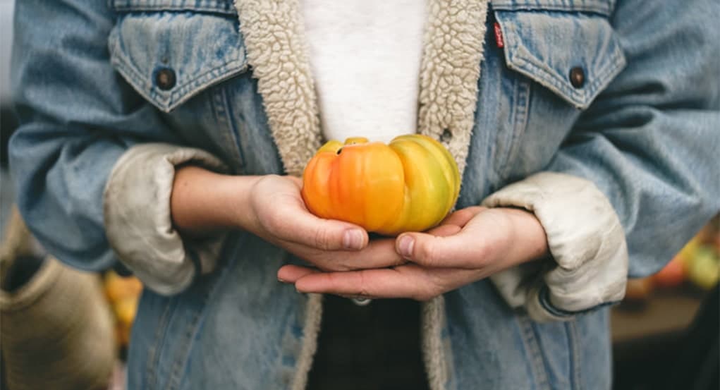 woman holding organic orange tomato
