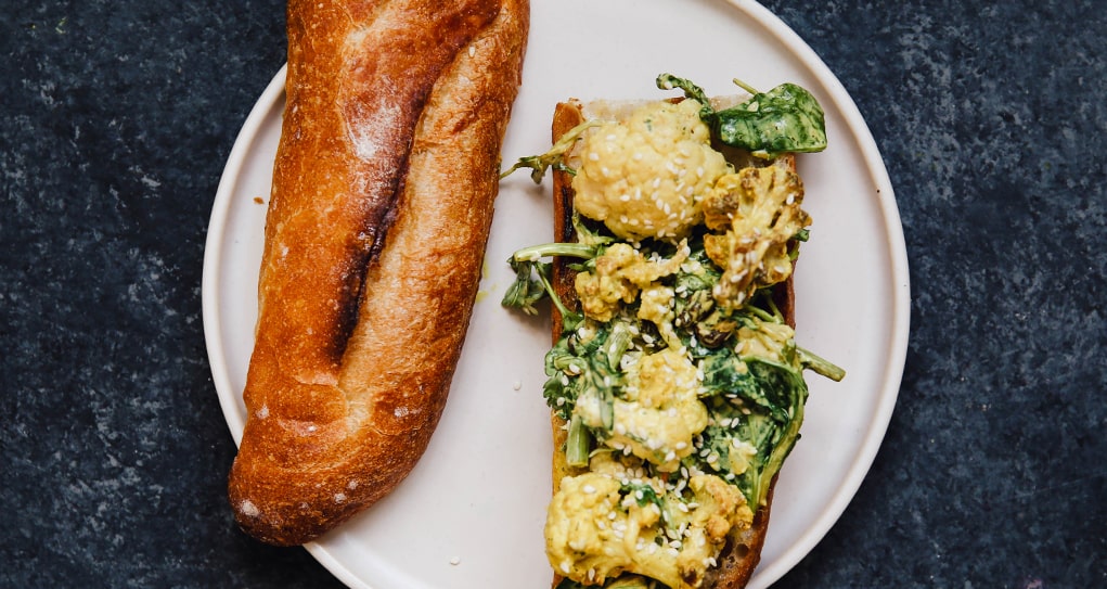 A toasted french baguette topped with curried cauliflower