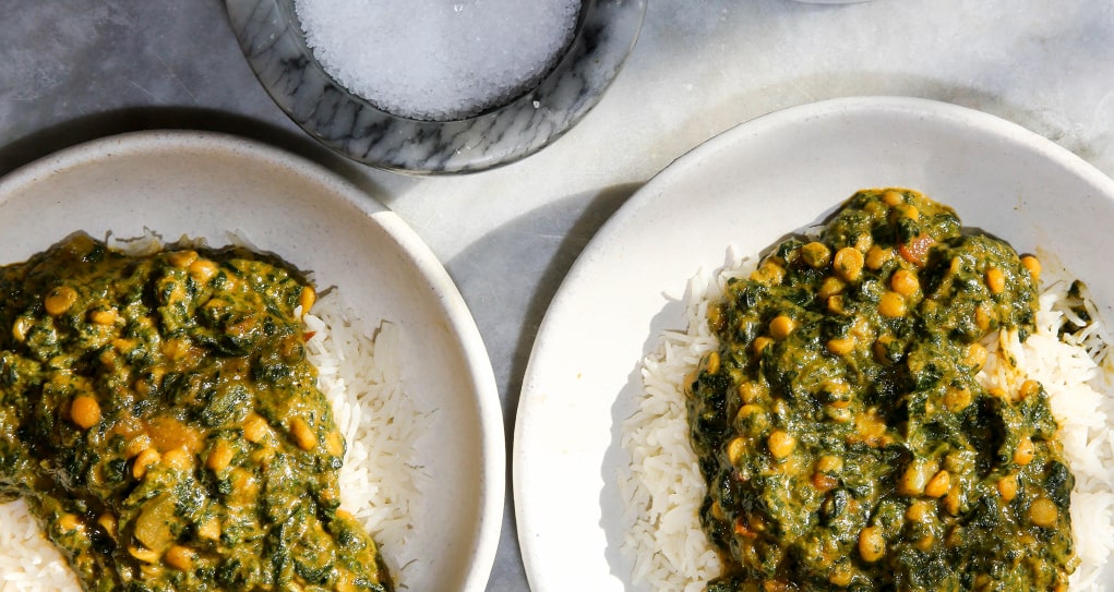 Two plates of dal saag over white rice