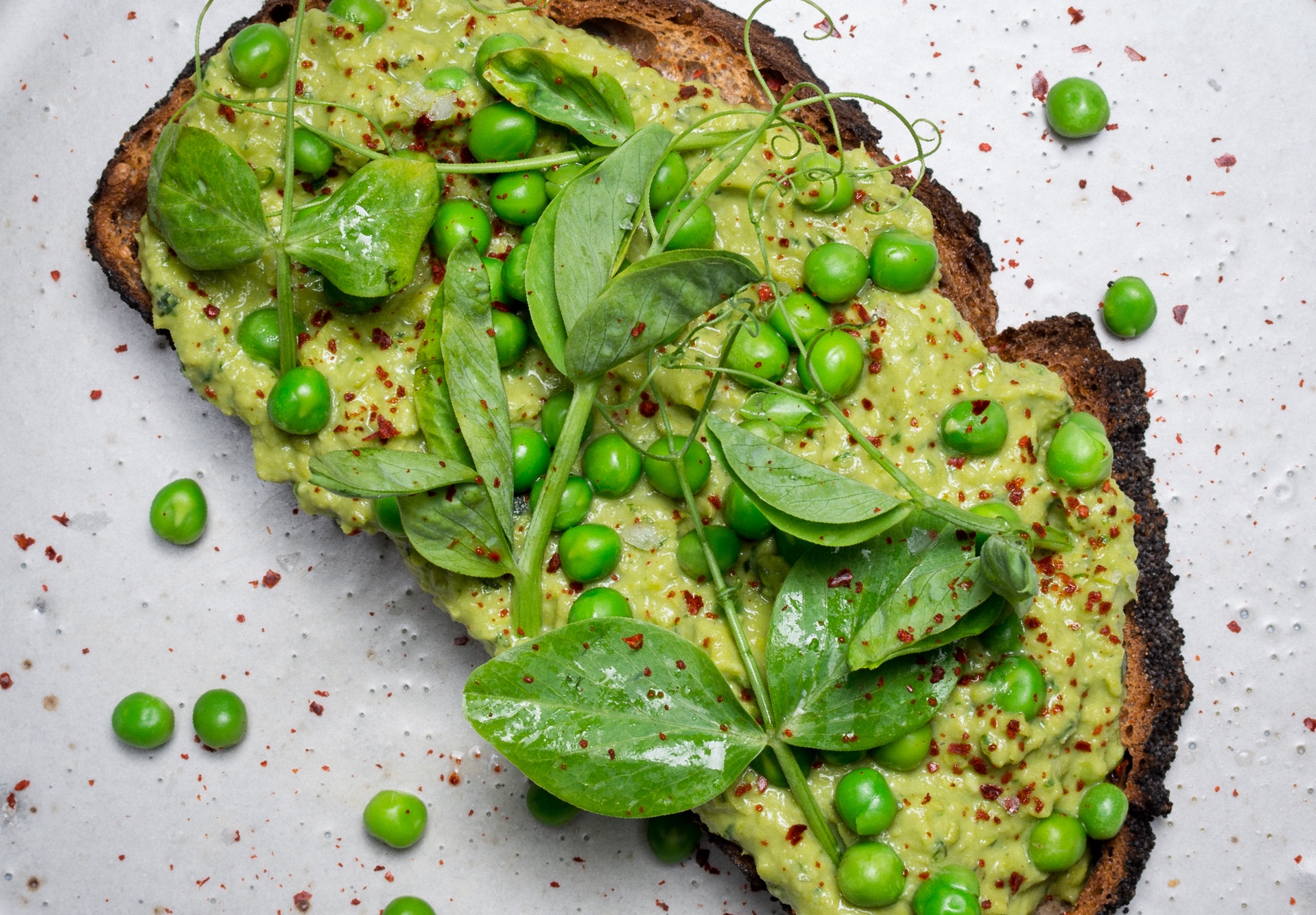 Top view of slice of rustic toast toipped with smashed peas.