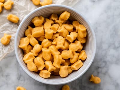 Vegan goldfish crackers in a bowl with some sprinkled on the counter.
