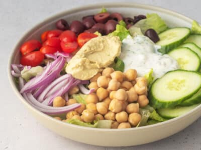 Mediterrenean bowl filled with veggies and topped with a vegan tzatziki sauce.