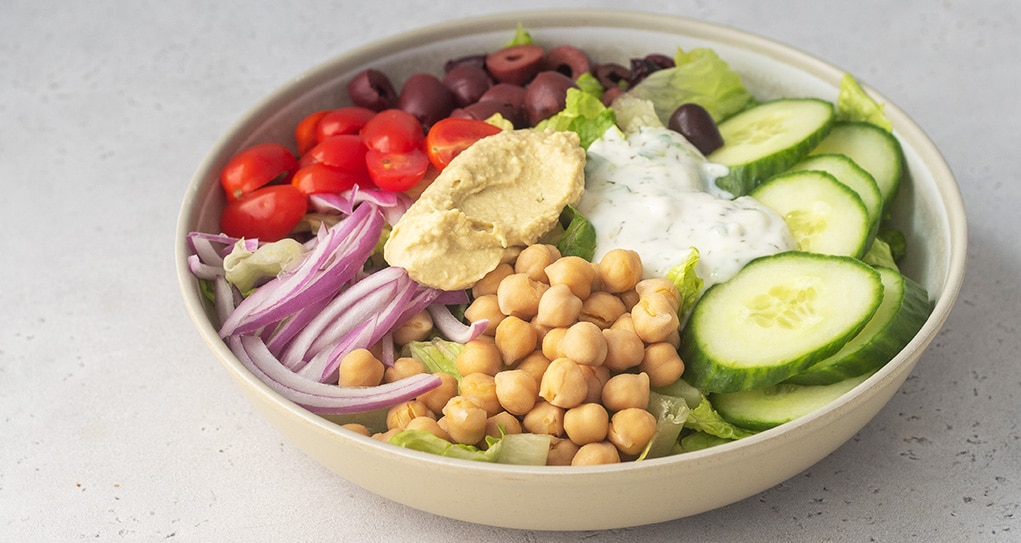 Mediterrenean bowl filled with veggies and topped with a vegan tzatziki sauce.