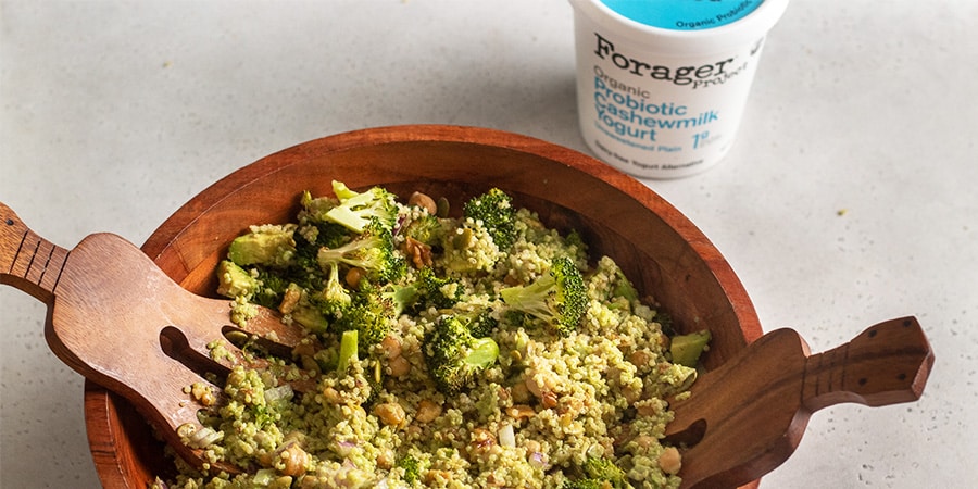 Broccoli Quinoa salad in a wooden bowl next to a tub of Forager Project Unsweetened Plain yogurt.